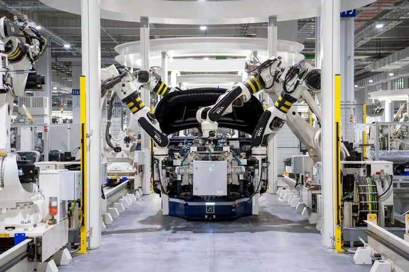 Célula de solda robotizada numa linha de montagem de carros, com robôs brancos em volta da carroceria